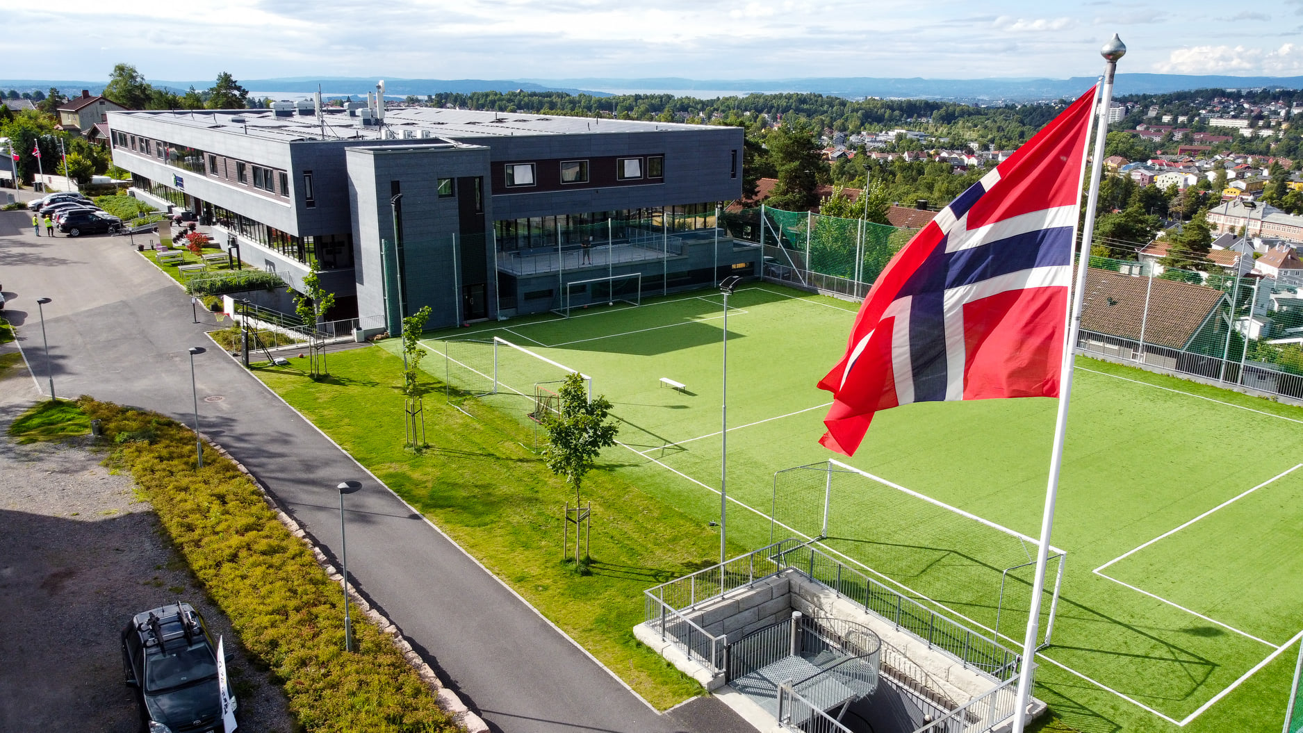 Skolebygg med kunstgress og flagg